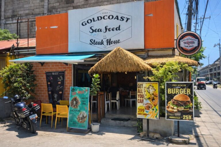 A restaurant with native entrance and a big orange white sign